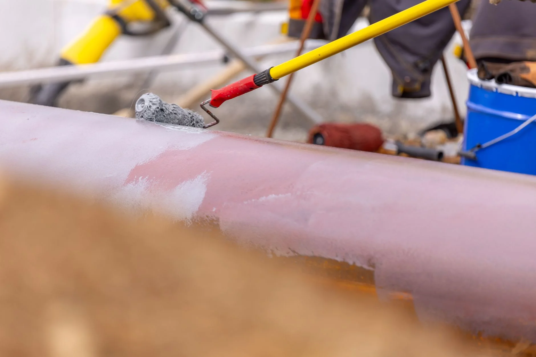 Protective coating applied with a roller to a large cylindrical component in a workshop