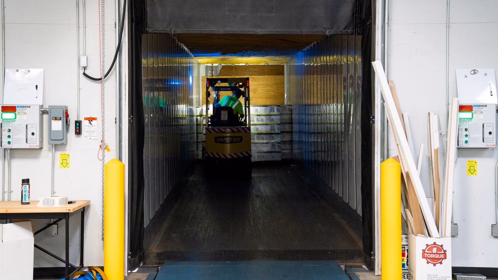 Forklift entering a loading dock protected by yellow bumpers