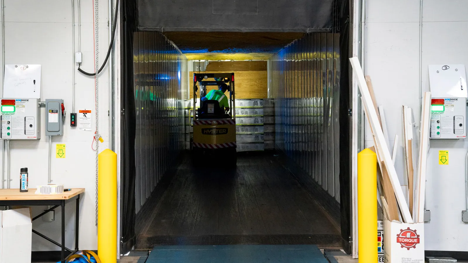 Chariot élévateur entrant dans un quai de chargement protégé par des butées d’impact jaunes