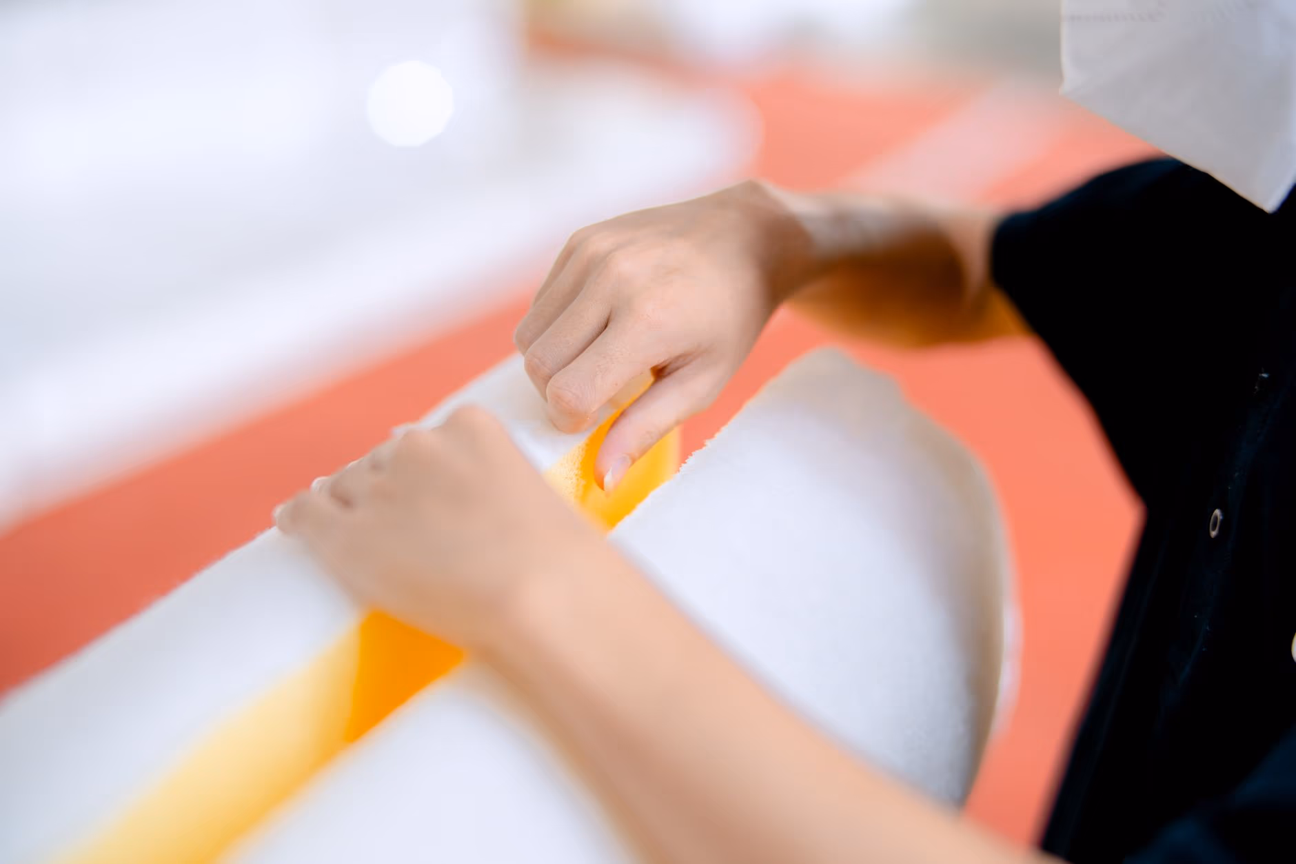Technician’s hands handling a soft yellow and white polymer material in a manufacturing shop