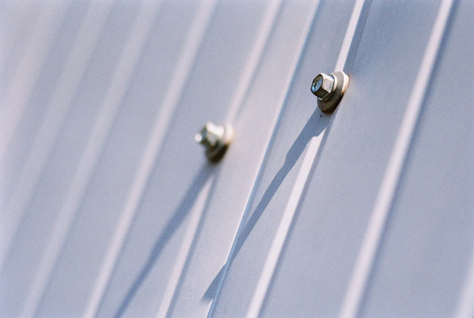 Bolts fastening a ribbed metal panel to industrial equipment